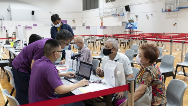 Health workers assist senior citizens registering for the Pfizer-BioNTech Covid-19 vaccine at the Senja-Cashew Community Centre Vaccination Centre, operated by Thomson Medical, in Singapore, on Monday, March 8, 2021. Singapore is introducing a program called Connect@Changi that will allow people to enter the island for business and official purposes without having to quarantine, provided they stay in a bubble-like facility near Changi Airport for the duration of their visit.