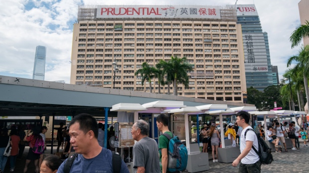 Pedestrians walk past as a banner featuring the Prudential Plc logo is displayed atop a building in Hong Kong, China, on Thursday, Aug. 9, 2018. Ping An Insurance (Group) Co. is considering buying Prudential's Asia business, people familiar with the matter said, a deal that would reshape Asia's booming insurance industry and mark the biggest-ever Chinese acquisition. Photographer: Anthony Kwan/Bloomberg