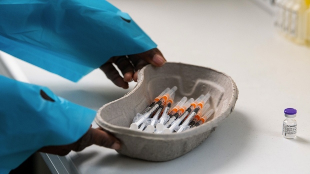 A health care worker places a dish of syringes near a vial of Covid-19 vaccine, produced by Pfizer Inc. and BioNTech SE, at a vaccination center in a town hall in Paris, France, on Friday, April 9, 2021. France met its target of inoculating 10 million people with a first dose of anti-Covid vaccine on Thursday, a week ahead of schedule, as the country endures its third lockdown. Photographer: Benjamin Girette/Bloomberg