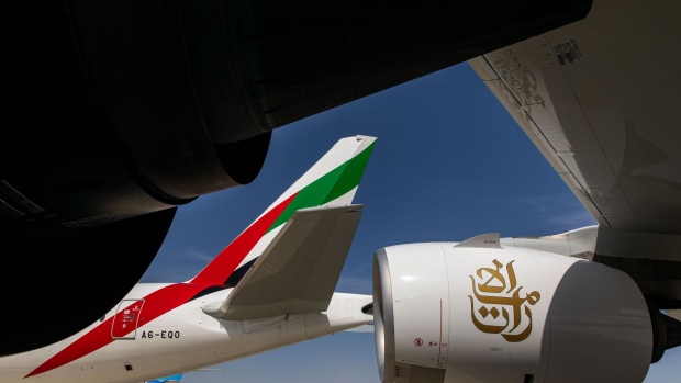 The logo of Emirates Airline sits on the tail fin of a Boeing Co. 777-300 aircraft, parked near an Airbus SE A380-800 aircraft with a Rolls Royce Holdings Plc engine, on the first day of the 16th Dubai Air Show at Dubai World Central (DWC) in Dubai, United Arab Emirates, on Sunday, Nov. 17, 2019. The Dubai Air Show is the biggest aerospace event in the Middle East, Asia and Africa and runs Nov. 17 - 21. Photographer: Christopher Pike/Bloomberg