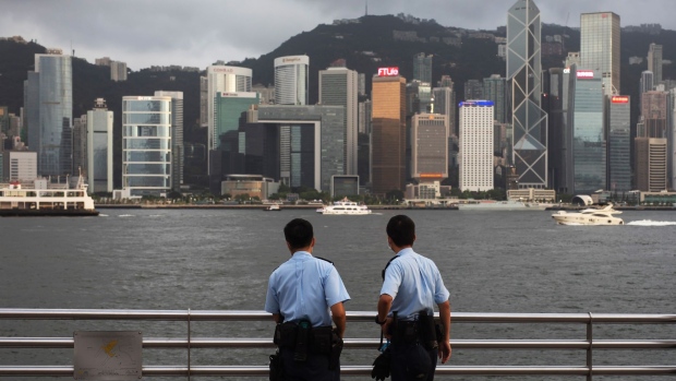 Police officers stand guard in front of the skyline at Tsim Sha Tsui in Hong Kong, China, on Thursday July, 1, 2021. Hong Kong's leader pledged to press ahead with an unprecedented national security crackdown, as the Asian financial center marked a series of fraught anniversaries symbolizing Beijing's tightening grip over local affairs. Photographer: Paul Yeung/Bloomberg