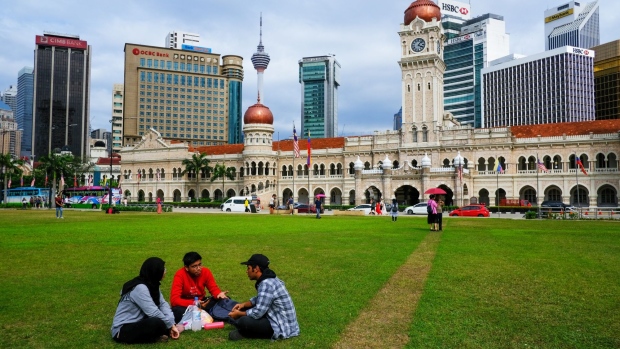 People sit on the lawn in front of the Sultan Abdul Samad building in Kuala Lumpur, Malaysia, on Monday, Jan. 6, 2020. Ringgit is poised for its first advance in three sessions, after overseas investors scooped up Malaysian stocks and the risk-off mood in global markets eased. Photographer: Samsul Said/Bloomberg