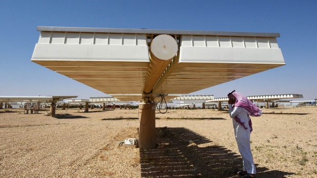 A Saudi man talks on a mobile phone under the shade of solar panel at a solar plant in Uyayna, north of Riyadh, on March 29.