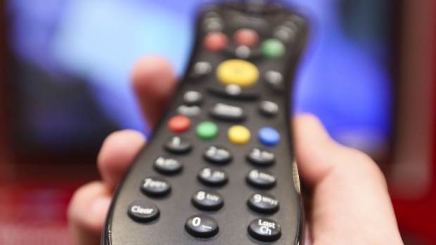 A man holds a television remote control unit.