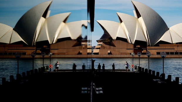 Pedestrians at promenade, opposite the Sydney Opera House, are reflected in a building at The Rocks in Sydney, Australia, on Monday, Aug. 30, 2021. Sydney had a record number of Covid-19 infections, accounting for the bulk of cases in New South Wales as Australia’s most populous state battles to contain the spread of the highly infectious delta variant.