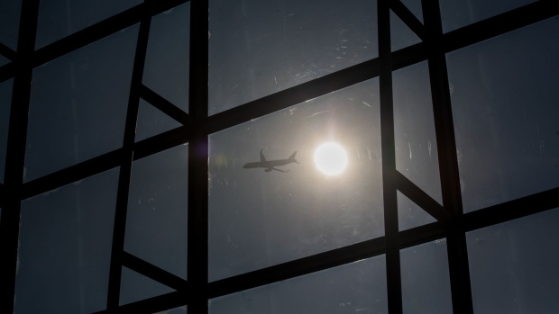An aircraft is silhouetted as it flies. Photographer: Paul Yeung/Bloomberg
