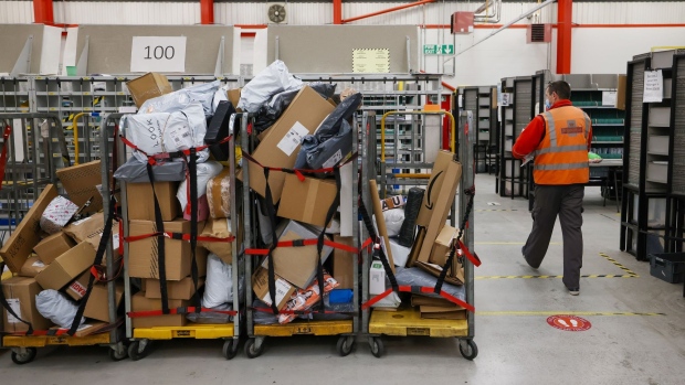 An employee passes trolleys loaded with parcels the Royal Mail Plc sorting office in Chelmsford, U.K., on Thursday, May 13, 2021. Royal Mail are due to report earnings on Thursday, May 20.