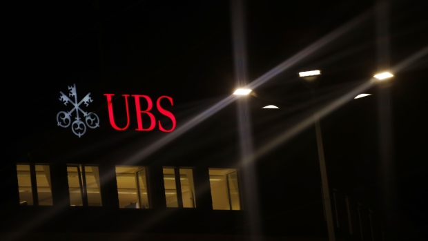 An illuminated company logo is displayed at a UBS Group AG bank branch in Zurich, Switzerland, on Monday, Oct. 14, 2019. The spying scandal roiling Credit Suisse Group AG has also created a big headache at UBS a stone's throw away in Zurich: What to do about its star hire Iqbal Khan. Photographer: Stefan Wermuth/Bloomberg