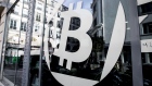 A logo sits on the windows of the offices of La Maison du Bitcoin bank in Paris, France, on Thursday, Nov. 23, 2017. Zimbabwe, where the price of bitcoin spiked to double the international rate after last week's military takeover, shows cryptocurrency skeptics where the real-world use of bitcoin, and possibly its future, lies.
