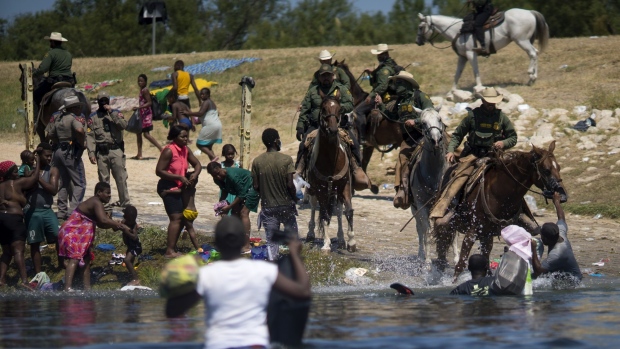 U.S. Border Patrol agents stop migrants crossing the Rio Grande River near the Del Rio-Acuna Port of Entry in Del Rio, Texas, U.S., on Sunday, Sept. 19, 2021. U.S. officials plan to expel thousands of Haitian migrants that arrived at the small Texas city of Del Rio this week.