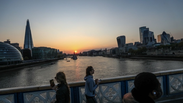 Pedestrians cross the River Thames on Tower Bridge as the sun sets in London, U.K., on Friday, April 24.