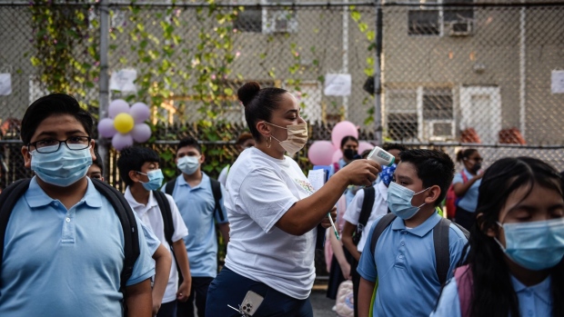 A teacher takes the temperature of students arriving on the first classes at a public school in the Bronx borough in New York, U.S., on Monday, Sept. 13, 2021. For the first time since the beginning of the Covid-19 pandemic, all of New York City’s public school students are expected to return to classes in person on Monday. Photographer: Stephanie Keith/Bloomberg