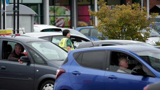 ELLESMERE PORT, UNITED KINGDOM - SEPTEMBER 24: A store worker directs traffic as people queue for petrol at a Morrisons Supermarket on September 24, 2021 in Ellesmere Port, United Kingdom. BP and Esso have announced that its ability to transport fuel from refineries to its branded petrol station forecourts is being impacted by the ongoing shortage of HGV drivers and as a result, it will be rationing deliveries to ensure continuity of supply. (Photo by Christopher Furlong/Getty Images)