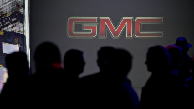 Attendees stand in front of a General Motors Co. (GM) logo during an unveiling event ahead of the 2017 North American International Auto Show (NAIAS) in Detroit, Michigan, U.S., on Sunday, Jan. 8, 2017. GM may test President-elect Donald Trump's patience with its new GMC Terrain -- shown for the first time tonight as the Detroit auto show opens -- when the upscale compact sport utility vehicle heads to U.S. dealers this year from Mexico. Photographer: Andrew Harrer/Bloomberg