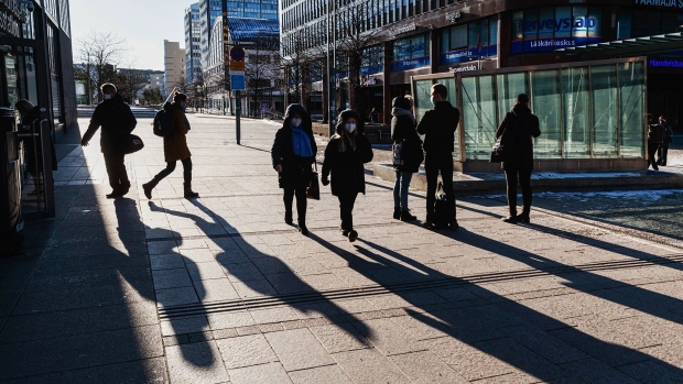 Pedestrians wearing protective face masks walk along a street in Helsinki, Finland, on Monday, March 8, 2021. Finland declared a state of emergency, allowing it to close bars and restaurants to curb the spread of the coronavirus. Photographer: Bloomberg/Bloomberg