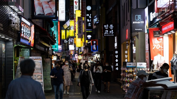 Pedestrians wearing protective masks walk through the Myeongdong shopping district of Seoul at night, South Korea, on Friday, Aug. 20, 2021. Focus is growing on whether the Bank of Korea can take the country's worst-ever virus wave in stride and tighten monetary policy on Aug. 26. Photographer: SeongJoon Cho/Bloomberg