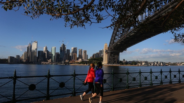 Runners jog along the boardwalk past the Sydney Harbor Bridge and the skyline of the central business district (CBD), in the Milsons Point suburb of Sydney,, Australia, on Tuesday, Sept. 28, 2021. Australian household spending declined for a third consecutive month as the delta variant of coronavirus swept the east coast and nation’s largest cities. Photographer: Lisa Maree Williams/Bloomberg