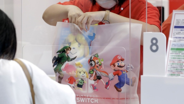 A store attendant wearing a protective mask puts a box of Nintendo Co. Switch game console in a shopping bag at the check-out counter inside the Nintendo TOKYO store in Tokyo, Japan, on Tuesday, Aug. 4, 2020. Nintendo is scheduled to report first-quarter earnings figures on Aug. 6. Photographer: Kiyoshi Ota/Bloomberg