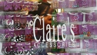 A customer browses a selection of earrings hanging in the front window of a Claire's store.