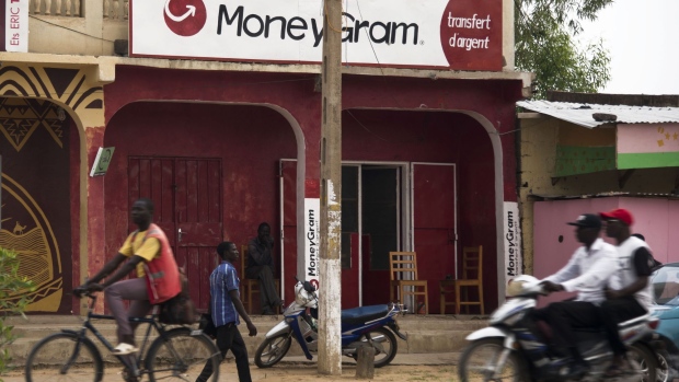 Pedestrians pass a MoneyGram International Inc. money transfer store in N'Djamena, Chad, on Wednesday, Aug. 16, 2017. African Development Bank and nations signed agreement to finance a project linking the town of Ngouandere in Cameroon and Chad’s capital, N’Djamena, according to statement handed to reporters in Cameroonian capital, Yaounde in July. Photographer: Xaume Olleros/Bloomberg