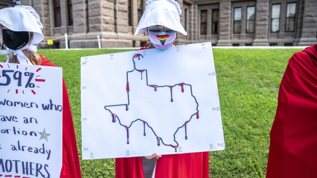 AUSTIN, TX - MAY 29: A protester dressed as a handmaiden holds up a sign at a protest outside the Texas state capitol on May 29, 2021 in Austin, Texas. Thousands of protesters came out in response to a new bill outlawing abortions after a fetal heartbeat is detected signed on Wednesday by Texas Governor Greg Abbot. (Photo by Sergio Flores/Getty Images) Photographer: Sergio Flores/Getty Images North America