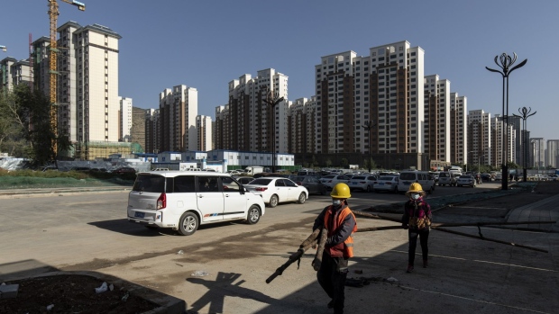 Workers carry wooden poles near apartment blocks under construction in the Nanchuan area of Xining, Qinghai province, China, on Tuesday, Sept. 28, 2021. China has urged financial institutions to help local governments stabilize the rapidly cooling housing market and protect the rights of some homebuyers, another signal that authorities are worried about fallout from the debt crisis at China Evergrande Group. Photographer: Qilai Shen/Bloomberg