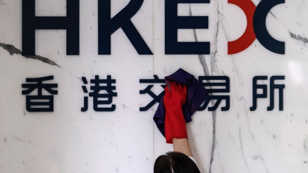 A worker cleans signage for Hong Kong Exchanges & Clearing Ltd. (HKEX) displayed at the Exchange Square complex in Hong Kong, China, on Wednesday, Aug. 19, 2020. HKEX posted a 1% gain in profit, benefiting from a spate of high-profile Chinese stock listings and a pick up in trading as the pandemic and political tensions stoked volatility. Photographer: Roy Liu/Bloomberg