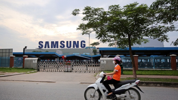 A motorcyclist rides past the Samsung Electronics Vietnam Co. Plant at Yen Phong Industrial Park in Bac Ninh Province, Vietnam, on Thursday, Sept. 1, 2016. Samsung Electronics Co. and its affiliate have built a factory town with 45,000 young workers and hundreds of foreign component suppliers -- a miniature version of the family-run chaebol conglomerates that dominate business back in Korea. The investment has been a windfall for businesses in Bac Ninh -- almost 2,000 new hotels and restaurants opened between 2011 and 2015 according to the provincial statistics office -- helping raise the province's per capita GDP to three times the national average. Photographer: Linh Luong Thai/Bloomberg