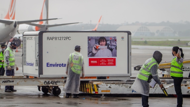 A worker performs a security check on a person before being allowed to go near a refrigerated container carrying Sinovac Biotech Ltd. coronavirus vaccines at Guarulhos International Airport (GRU) in Sao Paulo, Brazil, on Thursday, Nov. 19, 2020.The CoronaVac vaccine developed by China's Sinovac in partnership with Butantan Institute is able to produce an immune response in the body 28 days after its application in 97% of cases, according to results of clinical studies under phases 1 and 2 published at the Lancet Infectious Diseases magazine. Photographer: Jonne Roriz/Bloomberg