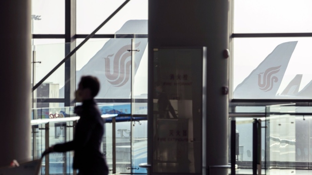 A passenger walks through a terminal in front of Air China Ltd. passenger aircraft at Shanghai Hongqiao International Airport in Shanghai, China, on Monday, March 29, 2021. Air China is scheduled to release earnings results on March 30. Photographer: Qilai Shen/Bloomberg