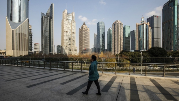 A pedestrian walks on an elevated walkway past buildings in Pudong's Lujiazui Financial District in Shanghai, China, on Friday, Dec. 28, 2018. China announced plans to rein in the expansion of lending by the nation's regional banks to areas beyond their home bases, the latest step policy makers have taken to defend against financial risk in the world's second-biggest economy.