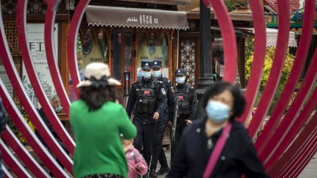 A squad of police officers wearing protective masks patrol the Xinjiang International Grand Bazaar in Urumqi, Xinjiang province, China, on Wednesday, May 12, 2021. China has told nations criticizing its policies in Xinjiang to stop interfering in domestic affairs.