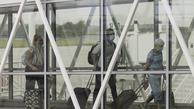 Travelers wearing protective face masks walk down a jet bridge at at Springfield-Branson National Airport (SGF) in Springfield, Missouri, U.S., on Thursday, Aug. 5, 2021. Citing a surge in unruly passengers, U.S. aviation regulators are calling on the nation's airports to encourage the police to arrest offenders, and to prevent people from sneaking alcohol on board. Photographer: Angus Mordant/Bloomberg