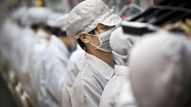 Employees of Hon Hai Precision Industry Co. Ltd. work along a production line in the Longhua Science and Technology Park, also known as Foxconn City, in Shenzhen, China.