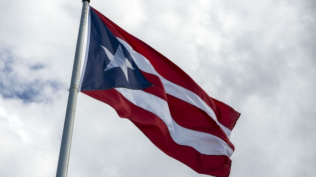 A Puerto Rican flag flies outside the Capitol of Puerto Rico building in San Juan, Puerto Rico, on Saturday, May 13, 2017. With Wall Street's help, the U.S. commonwealth borrowed tens of billions in the bond markets, only to squander much of it on grand projects, government bureaucracy, everyday expenses and worse. Debts were piled on debts, even as the economy gave way. Photographer: Xavier Garcia/Bloomberg