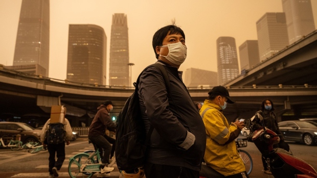 BEIJING, CHINA - APRIL 15: A commuter wears a protective mask as they wait at a traffic light during a seasonal sandstorm on April 15, 2021 in the Central Business District in Beijing, China. China's capital and the northern part of the country typically experience sandstorms that originate in the Gobi desert, but scientists believe that climate change and desertification also plays a role in their frequency and intensity. (Photo by Kevin Frayer/Getty Images)