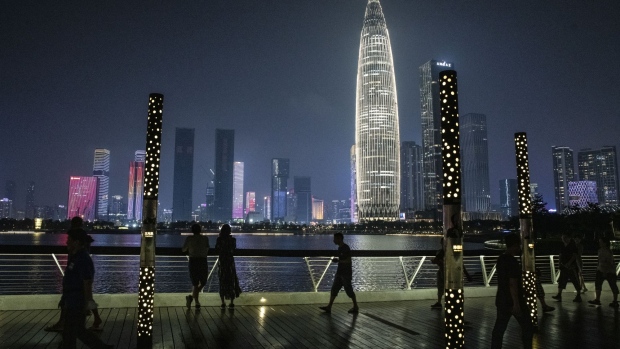 Pedestrians pass in front of the KK100 skyscraper while walking through a park at night in Shenzhen, China, on Thursday, Sept. 30, 2021. Over 20 Chinese regions are facing electricity cuts as the nation's power crisis deepens.
