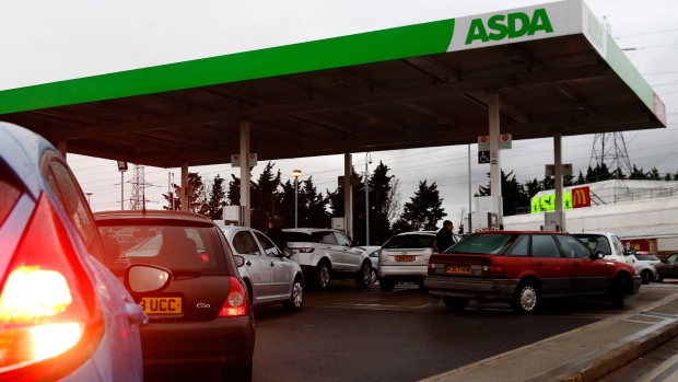 Cars wait in line to re-fuel at an ASDA Group Ltd. supermarket gas station in Croydon, U.K.