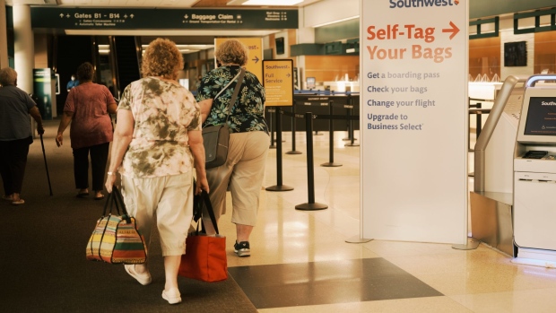 Travelers pass in front of Southwest Airlines self-service kiosks at Sarasota Bradenton International Airport (SRQ) in Sarasota, Florida, U.S., on Wednesday, Sept. 29, 2021. Airline losses from the coronavirus pandemic are set to surpass $200 billion as travel curbs weigh on corporate and long-haul demand well into 2022, according to the industry’s main lobby. Photographer: Zack Wittman/Bloomberg