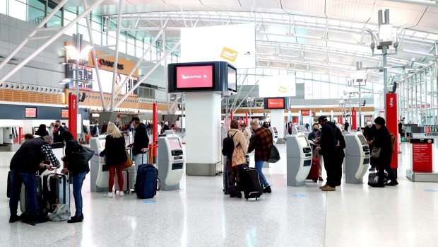 Travelers use self check-in kiosks for Qantas Airways Ltd. in a domestic terminal at Sydney Airport in Sydney, Australia, on Wednesday, June 23, 2021. While losses at airlines globally from Covid-19 are set to surpass $174 billion by the end of 2021 -- wiping out half a decade of profits -- Qantas has become one of the most financially secure carriers anywhere in the world. Photographer: Brendon Thorne/Bloomberg