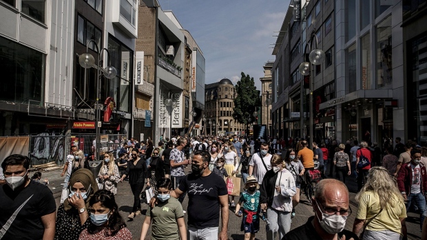 Shoppers wearing protective face masks pass retail outlets on Schildergasse in Cologne, Germany, on June 12, 2021. German Health Minister Jens Spahn suggested ending the mask mandate for outdoor activities as Covid-19 infections recede. Photographer: Sarah Pabst/Bloomberg