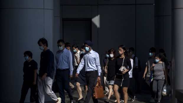 Morning commuters wearing protective masks make their way through Central district in Hong Kong, China, on Wednesday, Aug. 18, 2021. Hong Kong is caught between its desire to reopen and the government's zero tolerance for any cases of Covid-19, which has kept the virus out for most of the pandemic. Photographer: Paul Yeung/Bloomberg