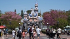 People wearing protective masks walk in front of Sleeping Beauty Castle during the reopening of the Disneyland theme park in Anaheim, California, U.S., on Friday, April 30, 2021. Walt Disney Co.’s original Disneyland resort in California is sold out for weekends through May, an indication of pent-up demand for leisure activities as the pandemic eases in the nation’s most-populous state. Photographer: Bing Guan/Bloomberg