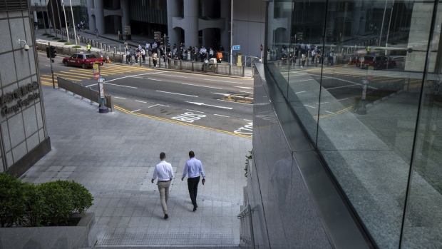 Morning commuters wearing protective masks cross a road in Central district in Hong Kong, China, on Wednesday, Aug. 18, 2021. Hong Kong is caught between its desire to reopen and the government's zero tolerance for any cases of Covid-19, which has kept the virus out for most of the pandemic.