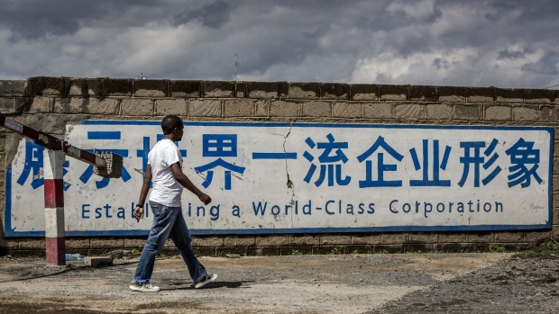 A pedestrian walks past a sign for China Communications Construction Co. outside their Standard Gauge Railway (SGR) line project headquarters in Maai Mahiu, Kenya, on Thursday, May 9, 2019. China is now the single largest financier for infrastructure in Africa, funding one-in-five projects and constructing every third one, according to a Deloitte report. Photographer: Luis Tato/Bloomberg