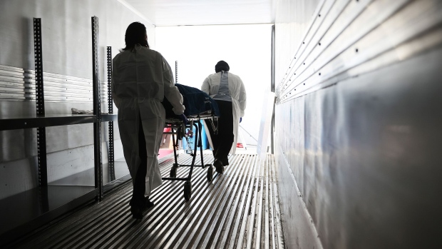 Maryland Cremation Services transporters Emma Tilghman (L) and Morgan Dean-McMillan wheel the remains of a coronavirus victim from inside a refrigerated truck trailer at Holy Cross Germantown Hospital May 11, 2020 in Germantown, Maryland. 