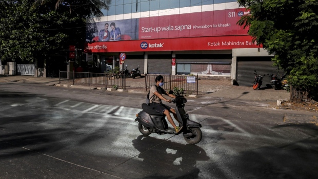 A motorcyclist wearing a protective mask rides past a Kotak Mahindra Bank Ltd. branch on a near-empty street in Mumbai, India, on Monday, May 4, 2020. India's central bank Governor Shaktikanta Das and the chief executive officers of the nation's banks have discussed ways to ensure credit flow to businesses once the world's toughest stay-at-home order ends.