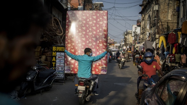 A rider on a motorcycle carries a mattress at a market in Lucknow, India, on Wednesday, Oct. 13, 2021. The Reserve Bank of India expects the months-long festival season to bolster urban demand in the second half of the financial year to March 2022, while rural demand will likely be buoyed by a robust monsoon and record food grain production.