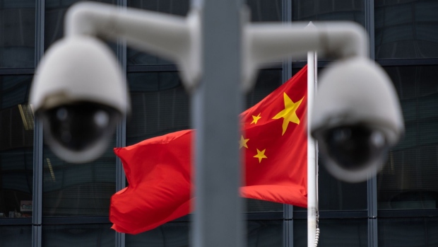 The flag of China is flown behind a pair of surveillance cameras outside the Central Government Offices in Hong Kong, China, on Tuesday, July 7, 2020. Hong Kong leader Carrie Lam defended national security legislation imposed on the city by China last week, hours after her government asserted broad new police powers, including warrant-less searches, online surveillance and property seizures. Photographer: Bloomberg/Bloomberg