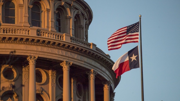 An American flag flies with the Texas state flag outside the Texas State Capitol building in Austin, Texas, U.S., on Tuesday, March 14, 2017. Austin has spent the last 10 months engaged in a big experiment in urban transportation. Several hundreds of thousands of people will descend upon Austin for the annual South by Southwest festival, a nine-day event that could be described as a tech conference, a music and film festival. Photographer: David Paul Morris/Bloomberg